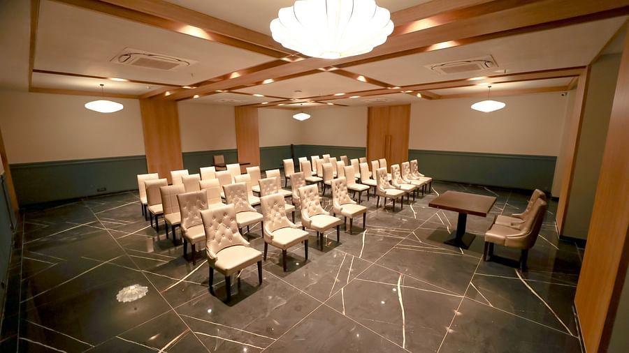 An image of a banquet hall with several chairs with a huge chandelier lights on top - Pride Resort Ambaji